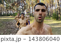 Group of young muscular athletes running at forest path. Active strong men jogging at sunny woodland. Male shirtless sportsmen training at summer nature. Concept of active and healthy lifestyle. POV 143806040