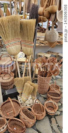 Traditional handmade brooms, woven wicker baskets, and wooden kitchen utensils displayed outdoor Traditional handmade brooms, woven wicker baskets, and wooden kitchen utensils displayed outdoor 143806308
