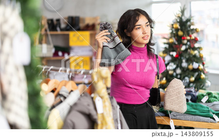 Asian woman will choose a warm hat against the background of a Christmas tree 143809155