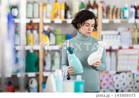 Adult woman chooses cleaning spray in store 143809373