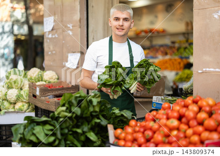 Guy shop seller puts spinach goods on display case Guy shop seller puts spinach goods on display case 143809374