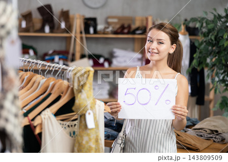 Girl with poster in hands announces discounts 50 percent in womens clothing store. Girl with poster in hands announces discounts 50 percent in womens clothing store. 143809509