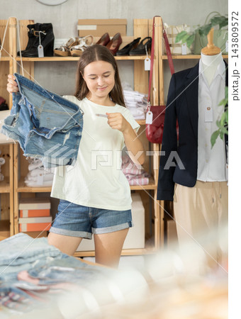 Teenage girl choosing jean shorts in clothing store Teenage girl choosing jean shorts in clothing store 143809572
