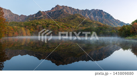 早朝の静寂に包まれる鏡池と水面に映り込む紅葉の戸隠連峰 143809880