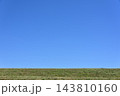 広い青空と緑の堤防が広がるシンプルな自然風景1 143810160