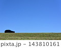 青空の下、緑の堤防を走る乗用車1 143810161