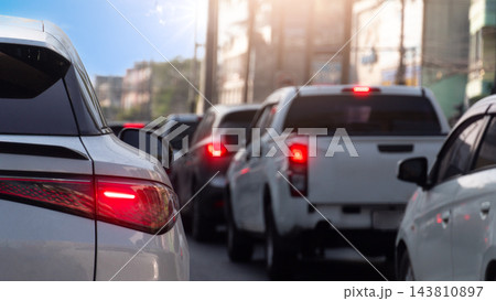 Rear view of cars stuck in slow moving traffic on an urban street during daytime. Highlighting glowing red tail lights and brake lights. Traffic jam in Thailand in business time with town background. Rear view of cars stuck in slow moving traffic on an urban street during daytime. Highlighting glowing red tail lights and brake lights. Traffic jam in Thailand in business time with town background. 143810897