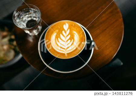 Top view of hot coffee latte art cup on small round wooden table 143811276