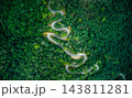 Top-down aerial view of curved road passing through lush green mountain forest 143811281