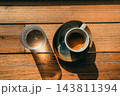 Flat lay of an espresso shot and a glass of water on a wooden table under bright sunlight 143811394