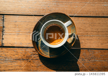 Close-up top view of a perfect espresso shot with golden crema in a ceramic cup on a wooden table Close-up top view of a perfect espresso shot with golden crema in a ceramic cup on a wooden table 143811395