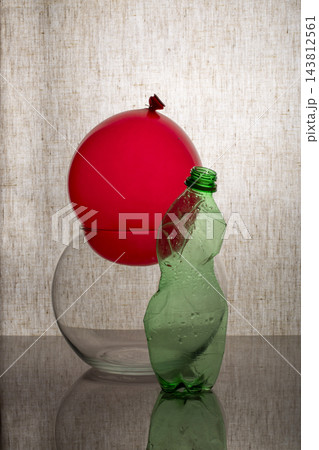 A crumpled plastic bottle and balloons on a gray background 143812561