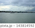 Cargo boats and vessels navigating the Hooghly river with Vidyasagar Setu bridge in the background under cloudy sky in Kolkata 143814592