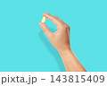 Omega 3. Person showcases omega fish oil capsule with bright backdrop. 143815409