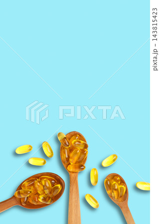 Omega 3. Golden omega fish oil capsules arranged in wooden spoons. Health supplement concept. 143815423