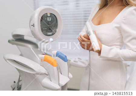 Cosmetologist hands adjusting settings on cosmetic ultrasound device touchscreen, preparing for professional facial lifting and skin rejuvenation procedure in modern beauty clinic, close-up. Cosmetologist hands adjusting settings on cosmetic ultrasound device touchscreen, preparing for professional facial lifting and skin rejuvenation procedure in modern beauty clinic, close-up. 143815513