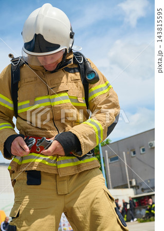 Firefighter In Full Protective Gear Adjusting Safety Harness And Belt During Training Or Emergency Response 143815595