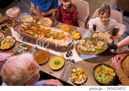 Multigenerational Family Sharing a Festive Middle Eastern Dinner Around a Large Platter 143815632
