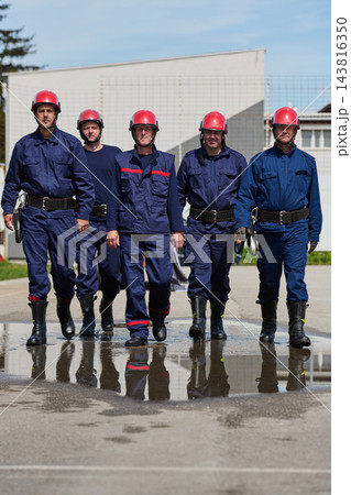 Firefighters Team Walking Together In Uniforms With Red Helmets Showing Teamwork And Readiness 143816350