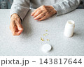 Elderly hands holding vitamin capsules with pill bottle on kitchen table for senior health 143817644