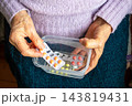 Elderly woman holding pill box with blister pack medication in hands at home 143819431