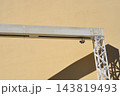 ndustrial white metal gate structure against a plain yellow wall background 143819493