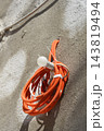 Coiled orange electrical conduit pipe with a light bulb on a concrete wall 143819494