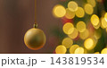 Christmas bauble hangs against glowing tree lights 143819534