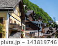 Traditional Alpine Houses with Wooden Balconies Nestled on Green Mountain Slope 143819746