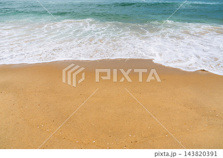 Gentle ocean waves washing over golden sand on a sunny beach in France, creating a peaceful coastal scene for summer travel and relaxation themes 143820391