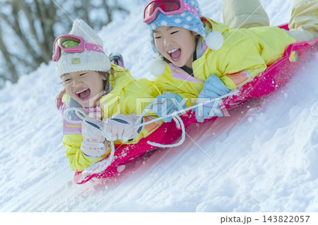 公園の雪の丘でそり遊びをする女の子たち 公園の雪の丘でそり遊びをする女の子たち 143822057