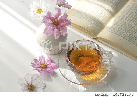 秋の日差しの中の紅茶と読書 ピンクのコスモスと開いた本のある暮らし 秋の日差しの中の紅茶と読書 ピンクのコスモスと開いた本のある暮らし 143822179