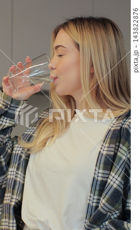 Attractive girl drinking water on domestic kitchen. Health and diet concept. 143822876