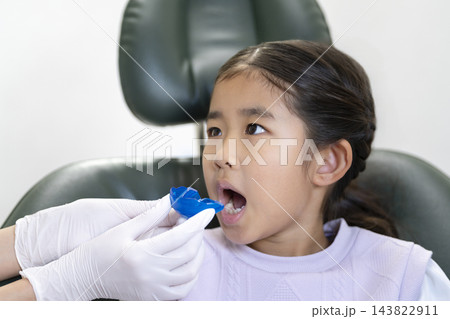 歯科医院で矯正用マウスピースの説明を受ける6歳の女の子 歯科医院で矯正用マウスピースの説明を受ける6歳の女の子 143822911