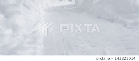 Cleared snowy path between snowdrift banks, shoveled walkway in winter. Footpath trail through snow after blizzard aftermath, pile on both sides. Close up texture with frost, blur and copy 143823014