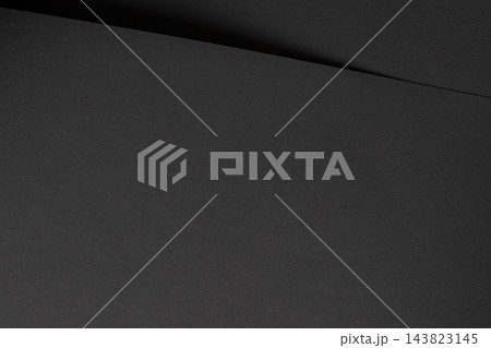 Dark grey paper texture, black sheet with diagonal fold and crease. Charcoal matte surface close up, fine grain fiber with bent edge and shadow. Monochrome backdrop, sleek minimalistic 143823145