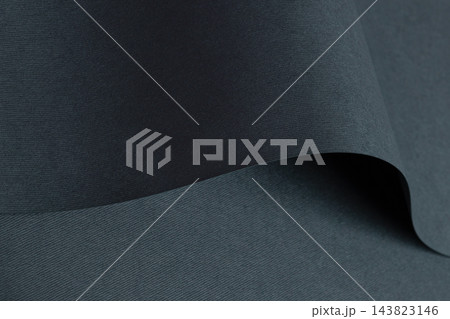 Navy fabric texture, folded twill with dark grey woven fold and curve. Bent edge, wave shape in close up, matte charcoal surface with diagonal grain. Smooth drape, deep blue monochrome 143823146