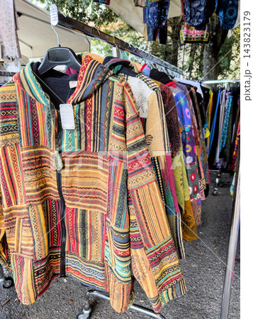 Striped patchwork hooded jacket on hanger at boho clothing stall Striped patchwork hooded jacket on hanger at boho clothing stall 143823179
