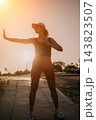 Fitness woman exercising outdoor workout practicing martial arts in a park at sunset with copy space for wellness lifestyle concepts 143823507