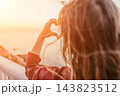 Heart Hands Sunset Woman making a heart gesture with her hands against a bright golden sunset by the sea during summer 143823512