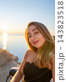 Woman sunset portrait of a smiling woman outdoors by the sea during golden hour expressing a serene vacation mood 143823518