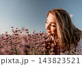 Lavender field woman smelling fragrant purple flowers in a blooming meadow during sunset with clear blue sky copy space 143823521