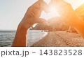 Heart sunset beach hands creating a romantic heart shape around the sun at the coastline during golden hour 143823528