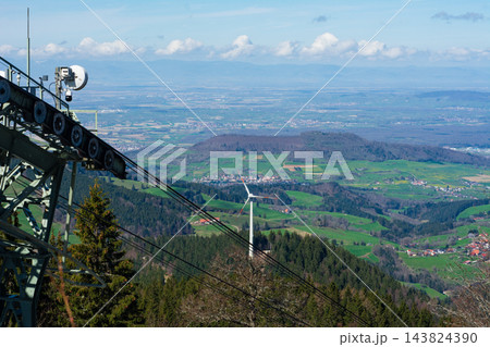 Stunning panoramic views from the mountaintop revealing lush valleys, wind turbines, and a cable car system during a clear day in the Alps of Switzerland 143824390