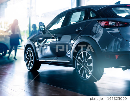 New SUV displayed in a modern luxury car showroom with blurred saleswoman and customer. Automobile dealership, vehicle purchase, financing and leasing services. Automotive sales and ownership services New SUV displayed in a modern luxury car showroom with blurred saleswoman and customer. Automobile dealership, vehicle purchase, financing and leasing services. Automotive sales and ownership services 143825090