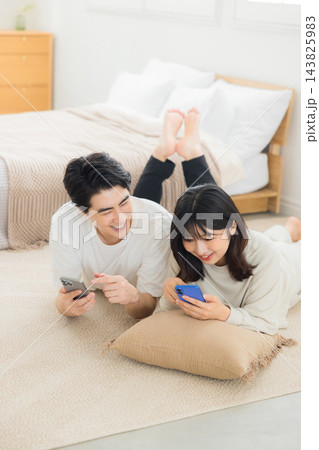 ベッドでスマホを見るカップル ベッドでスマホを見るカップル 143825983