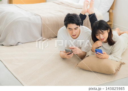 ベッドでスマホを見るカップル 143825985
