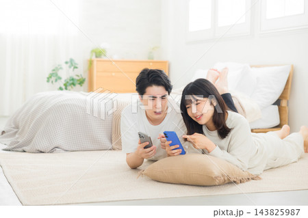 ベッドでスマホを見るカップル ベッドでスマホを見るカップル 143825987