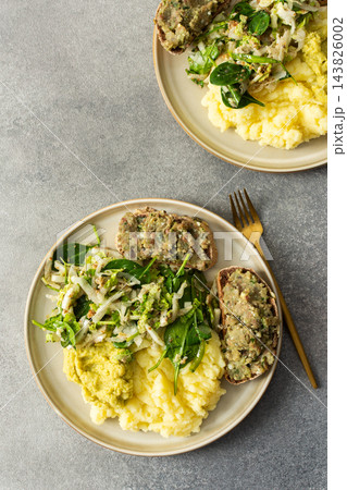Boiled potatoes are served with hummus alongside a gluten free sandwich filled with herring mince and fresh salad on a simple plate during breakfast time 143826002