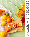 Citrus fruits are being prepared for Christmas drying. Different types of citrus are placed on a cutting board and drying rack in a home kitchen. The scene shows a festive activity 143826023